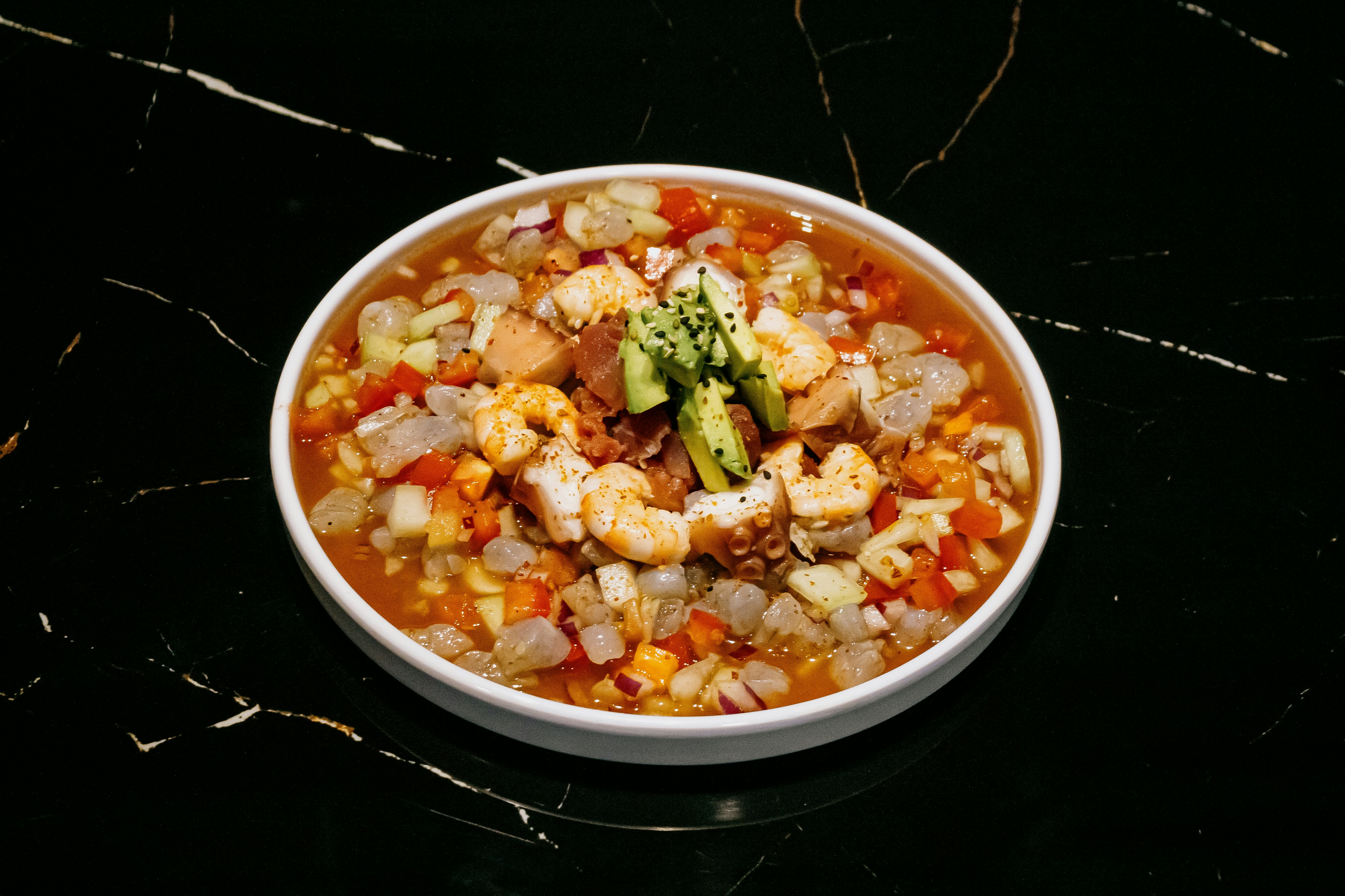 A white bowl filled with food on top of a black table