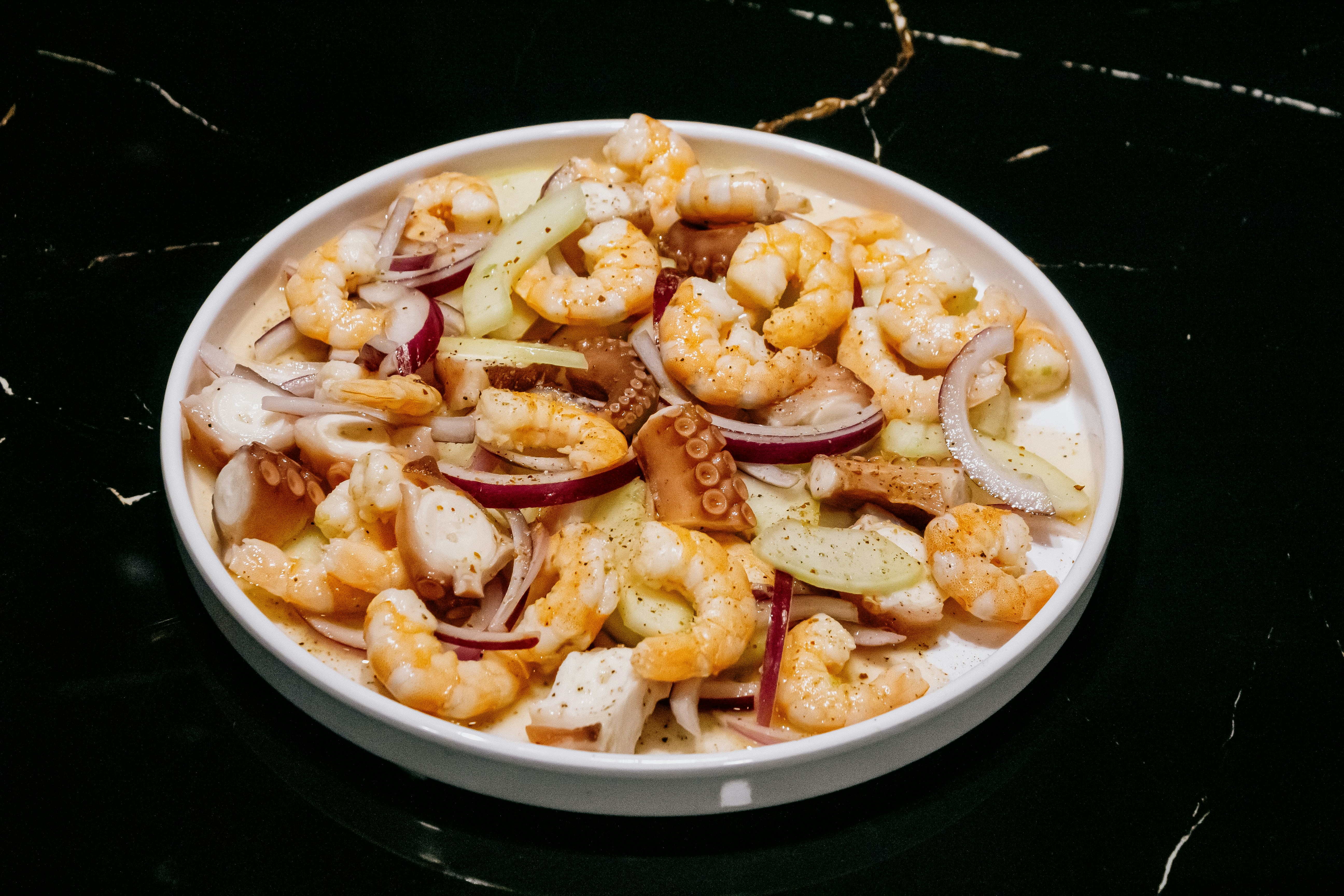 A white bowl filled with shrimp and onions