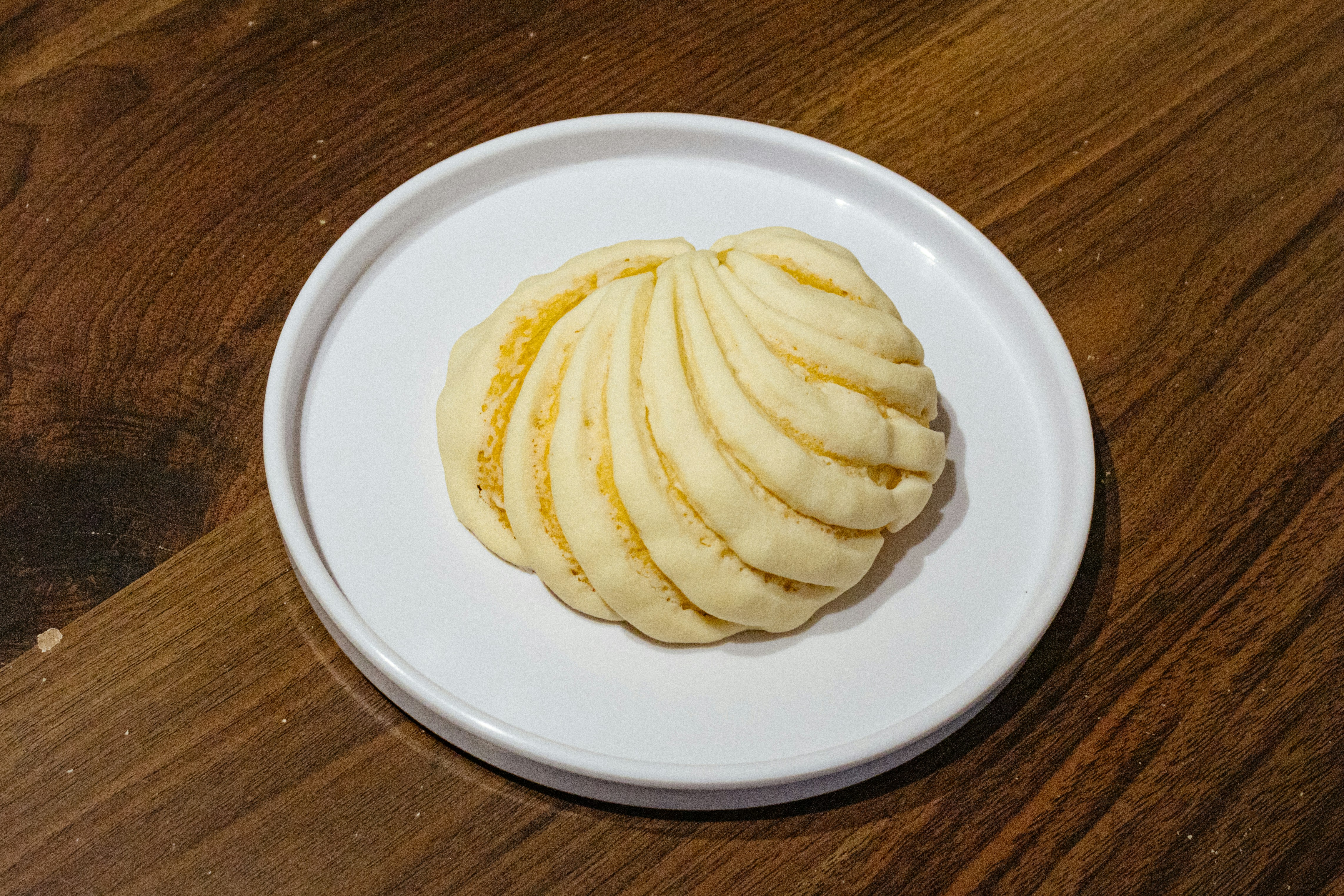 A white plate topped with sliced potatoes on top of a wooden table