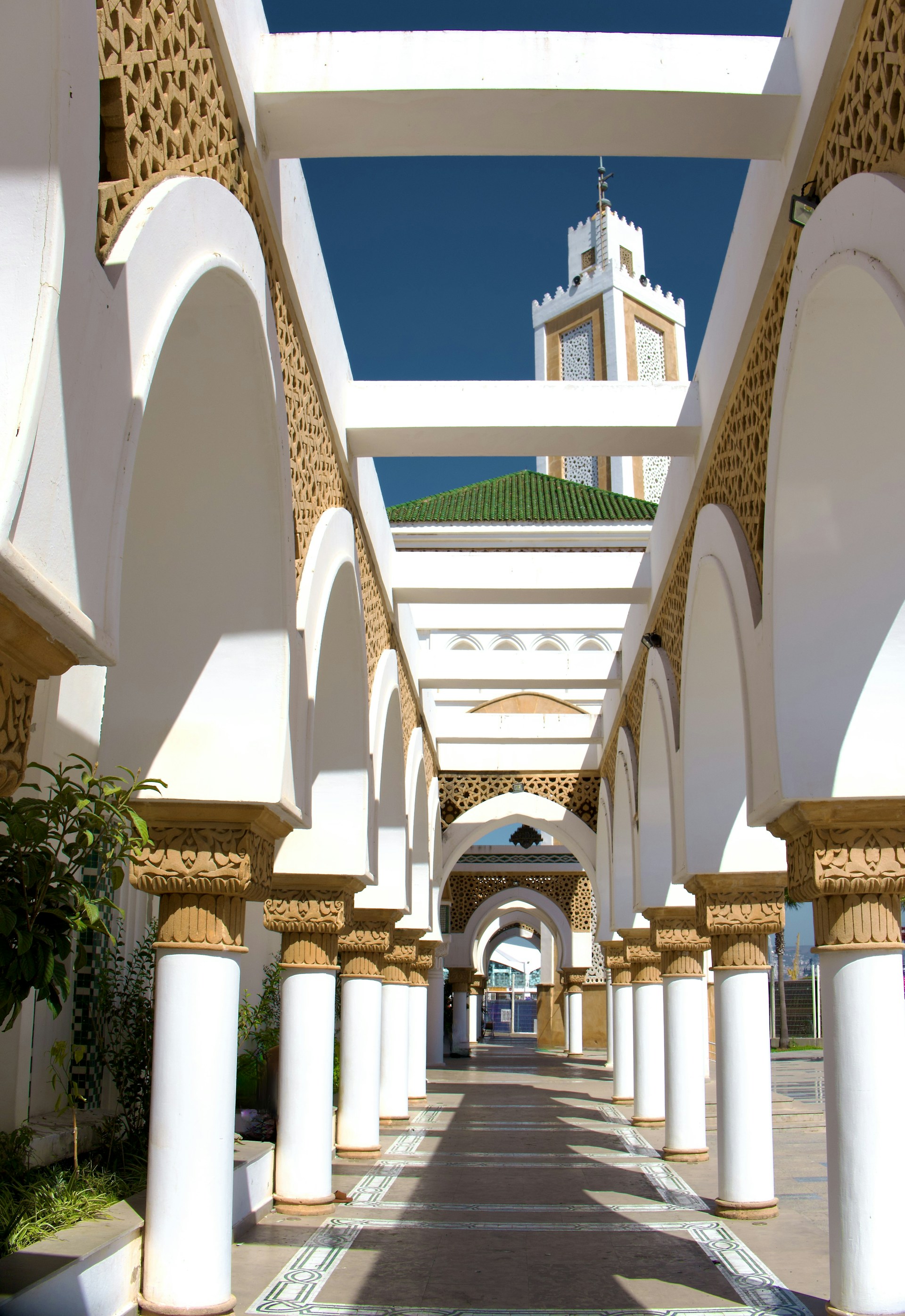 A walkway lined with columns and arches with a clock tower in the background