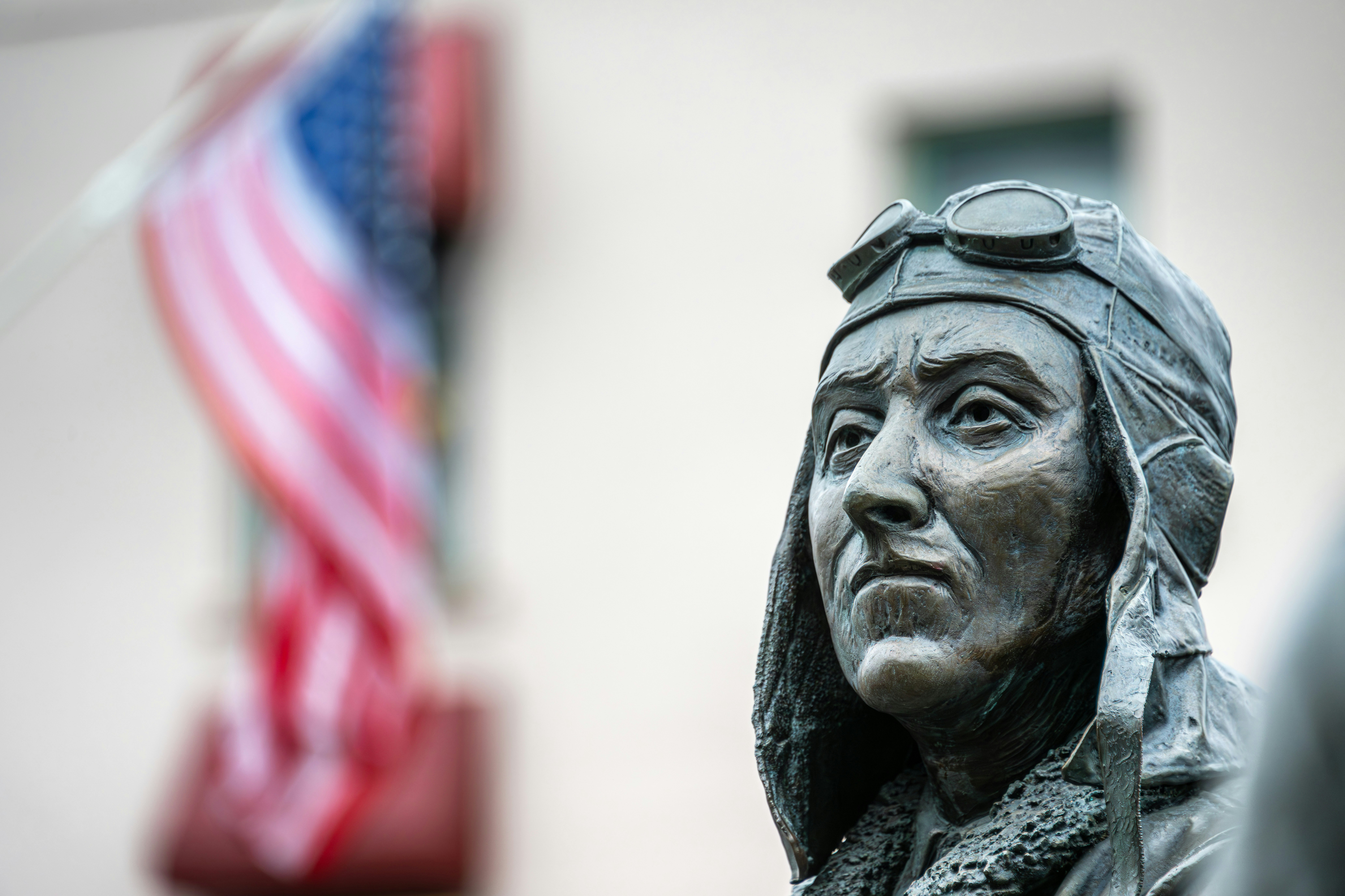 A statue of a woman with an american flag in the background, Close-up of a bronze bush pilot statue from 