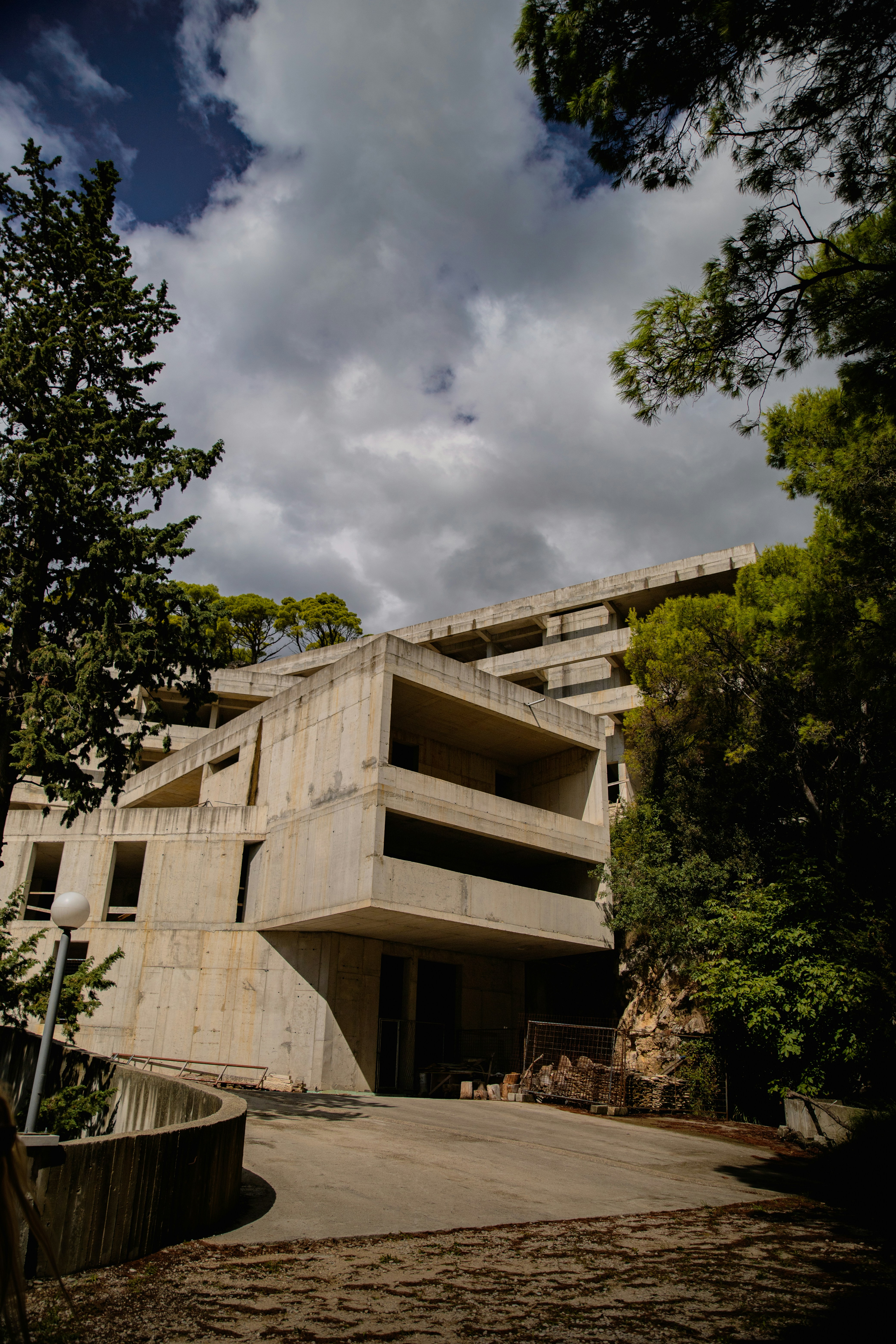 Ein Betongebäude, umgeben von Bäumen unter einem wolkenverhangenen Himmel