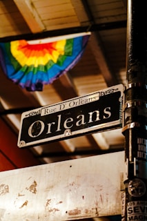 A street sign on a pole in front of a rainbow flag