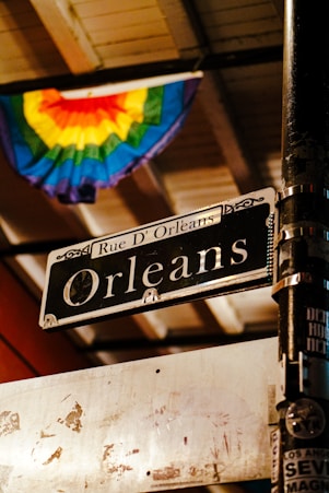 A street sign on a pole in front of a rainbow flag