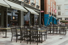 A row of tables and chairs sitting on a sidewalk