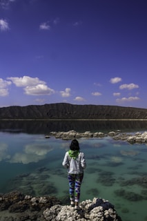 A person standing on a rock near a body of water