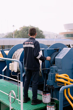 A man standing on top of a green platform next to a machine