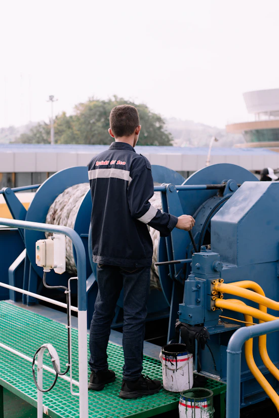 A man standing on top of a green platform next to a machine
