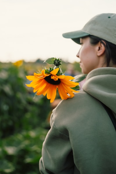 A woman in a green jacket and a sunflower