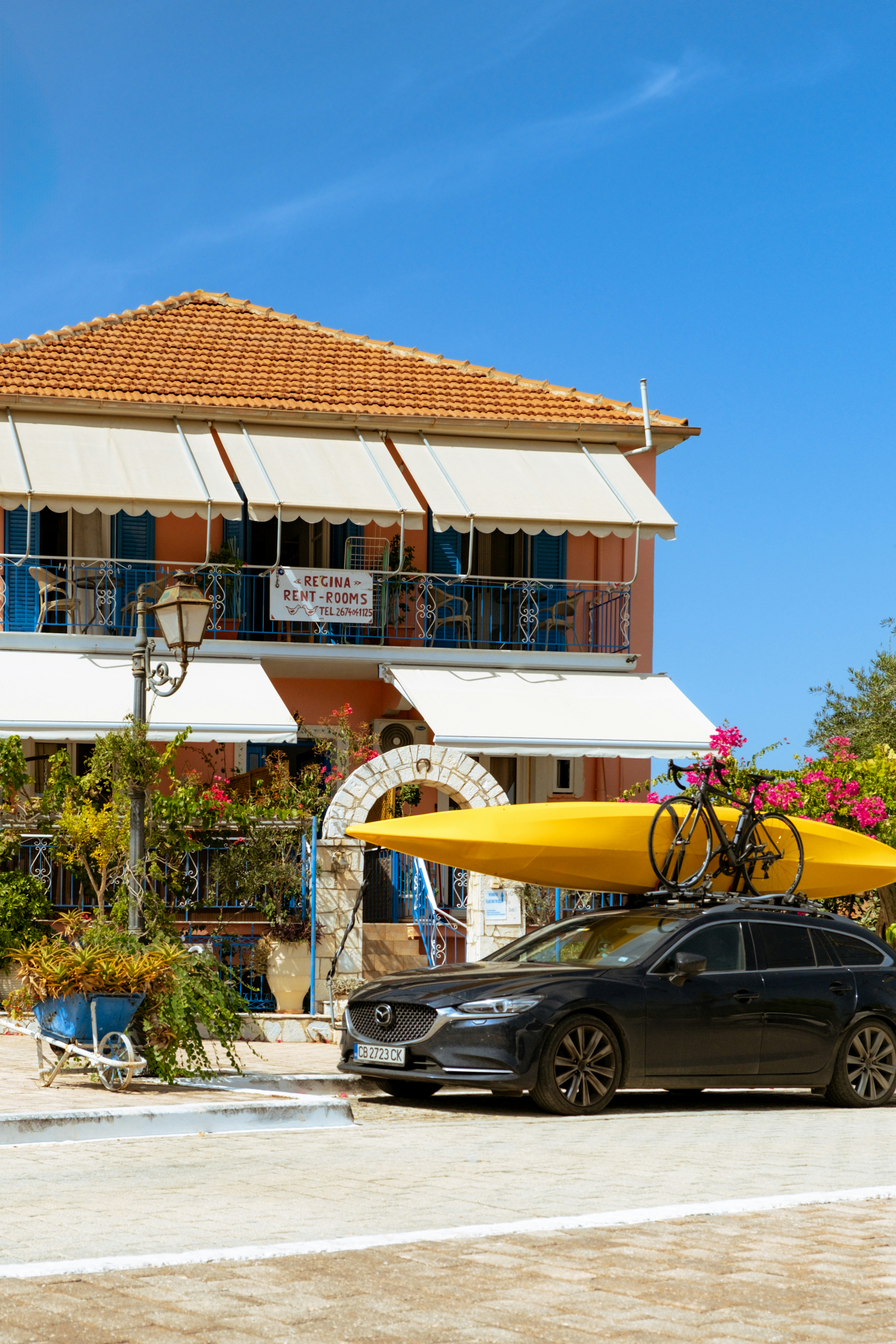 A car parked in front of a building with a surfboard on top of it