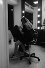 A woman sitting in a chair in front of a mirror