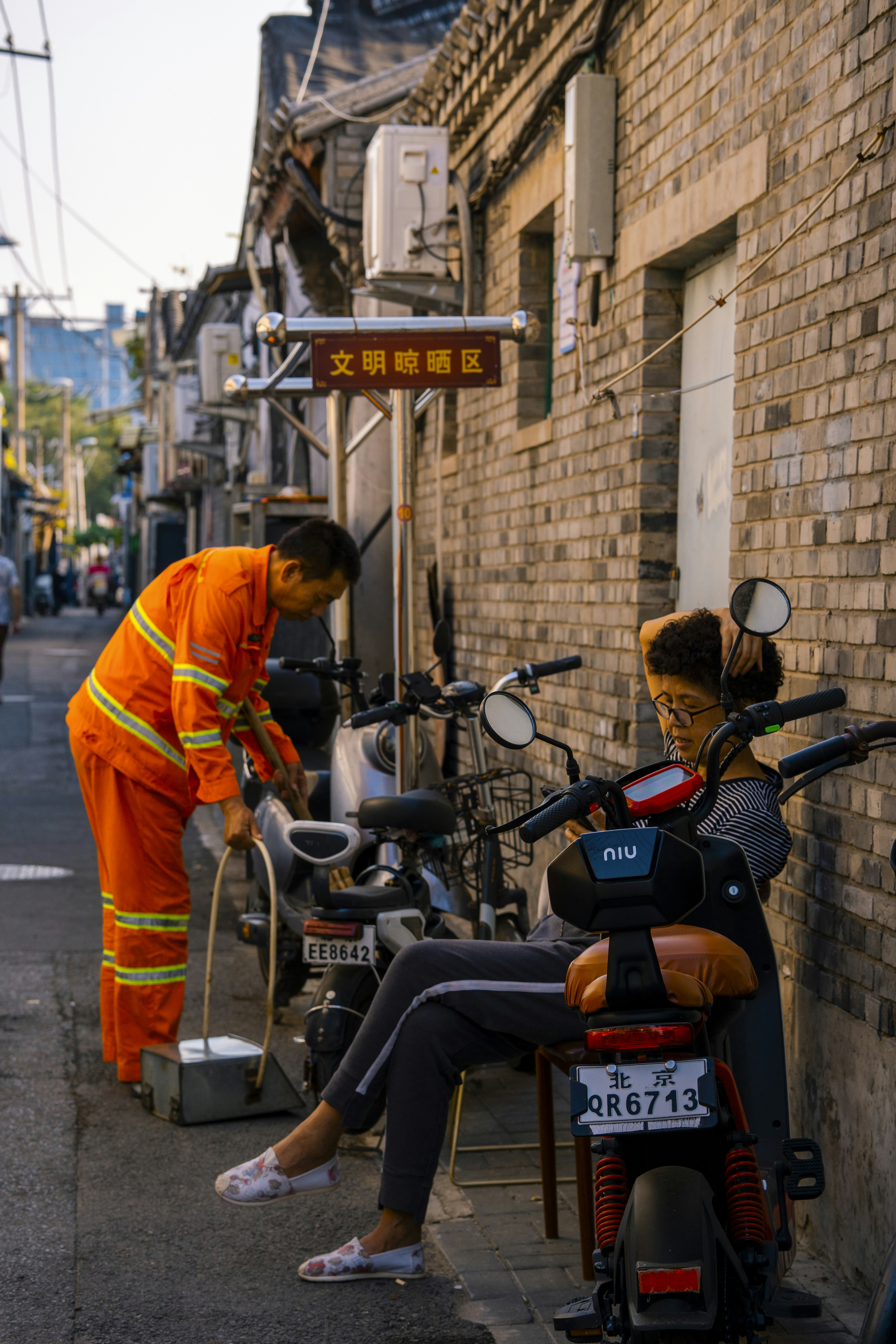 A man in an orange jumpsuit standing next to a woman on a scoot