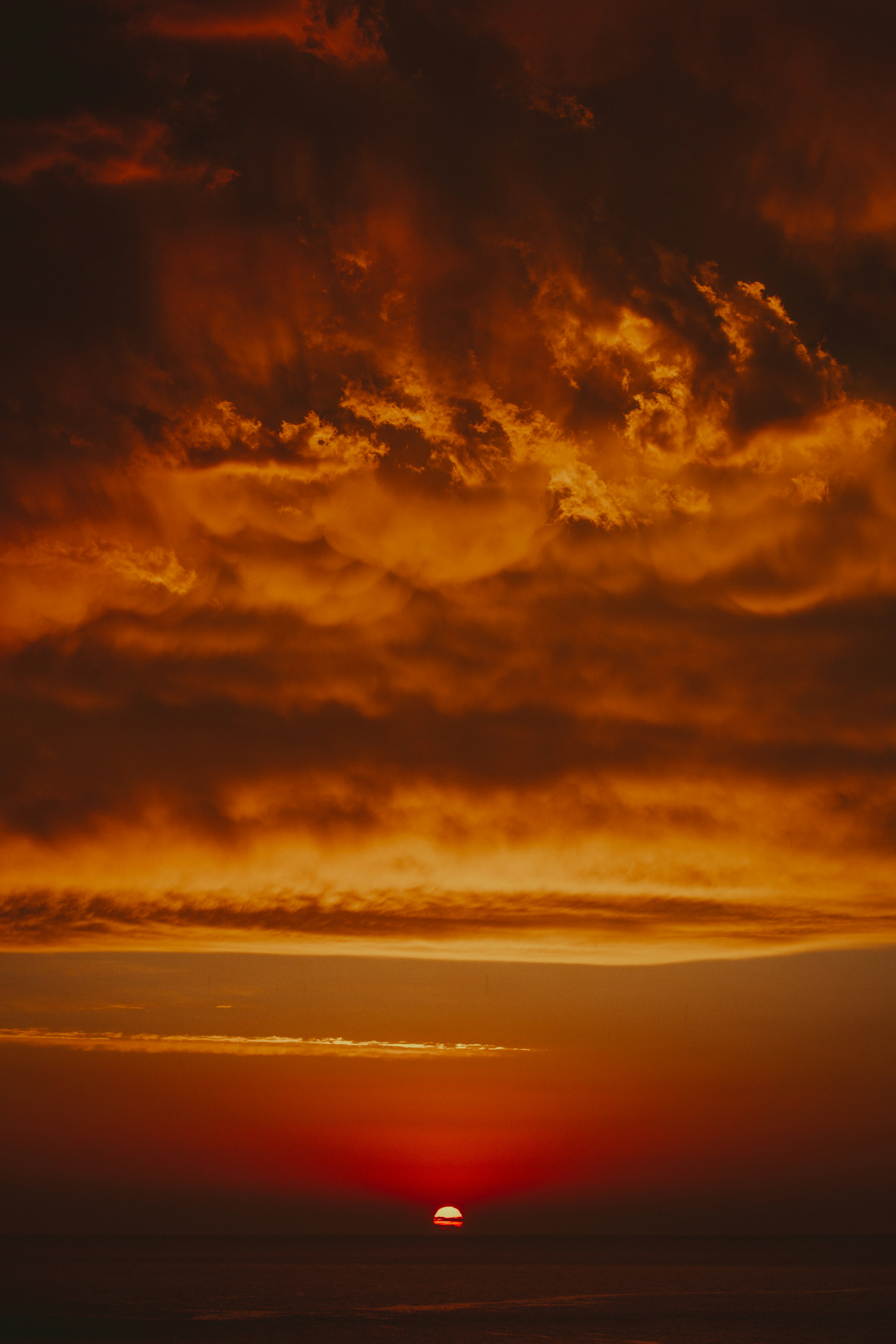 The sun is setting over the ocean on a cloudy day
