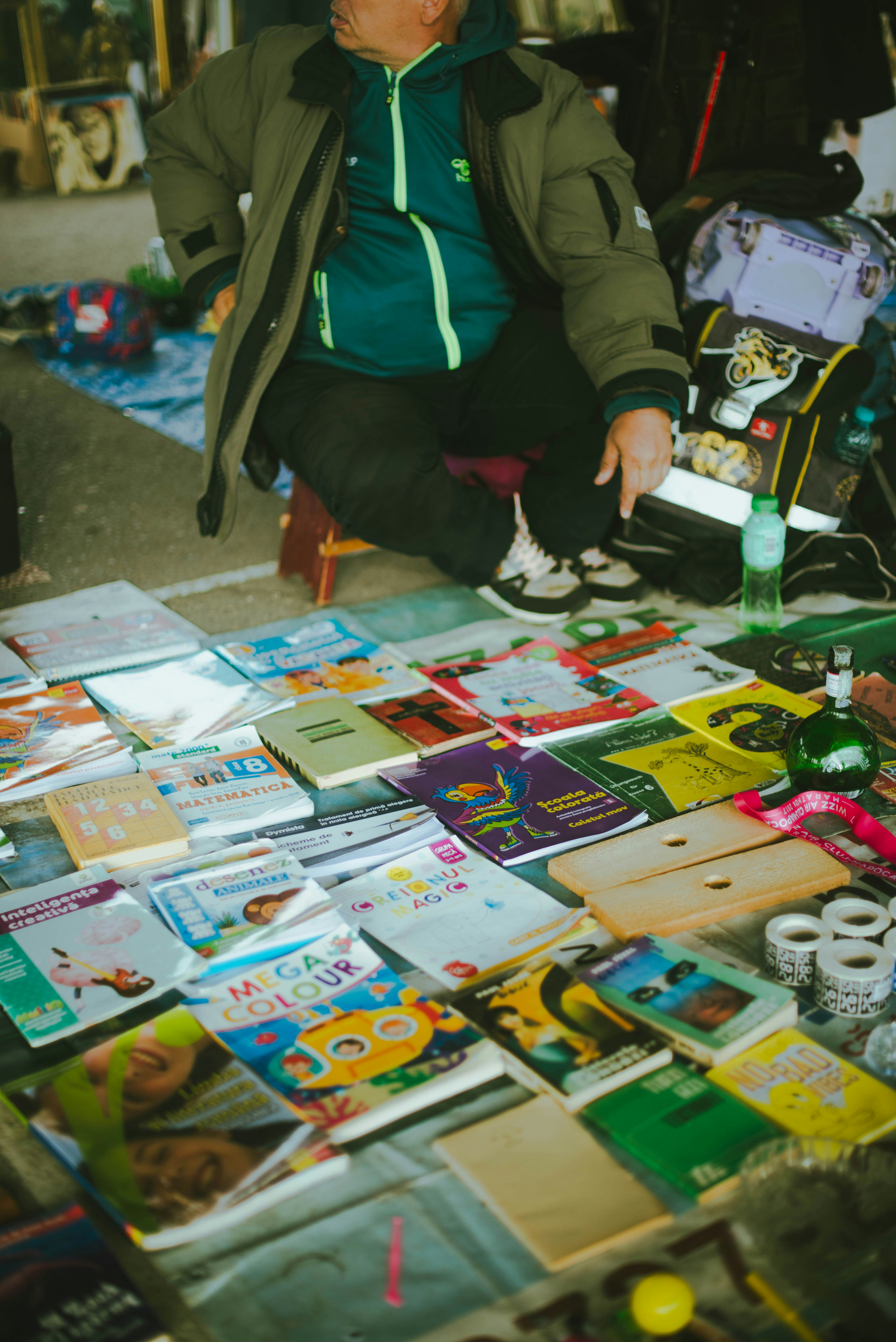 A man sitting on the ground next to a pile of books
