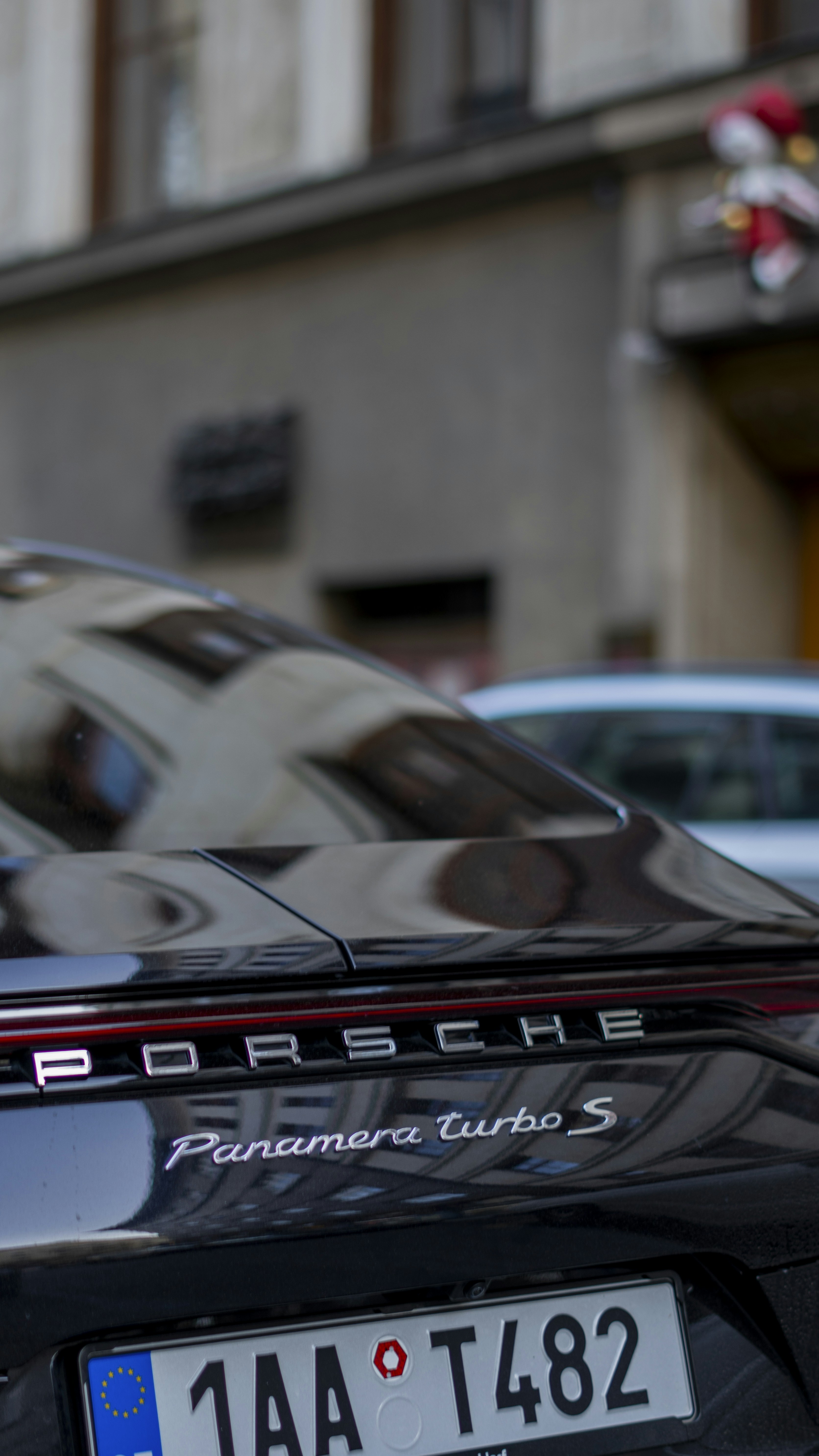 Une porsche noire garée devant un immeuble