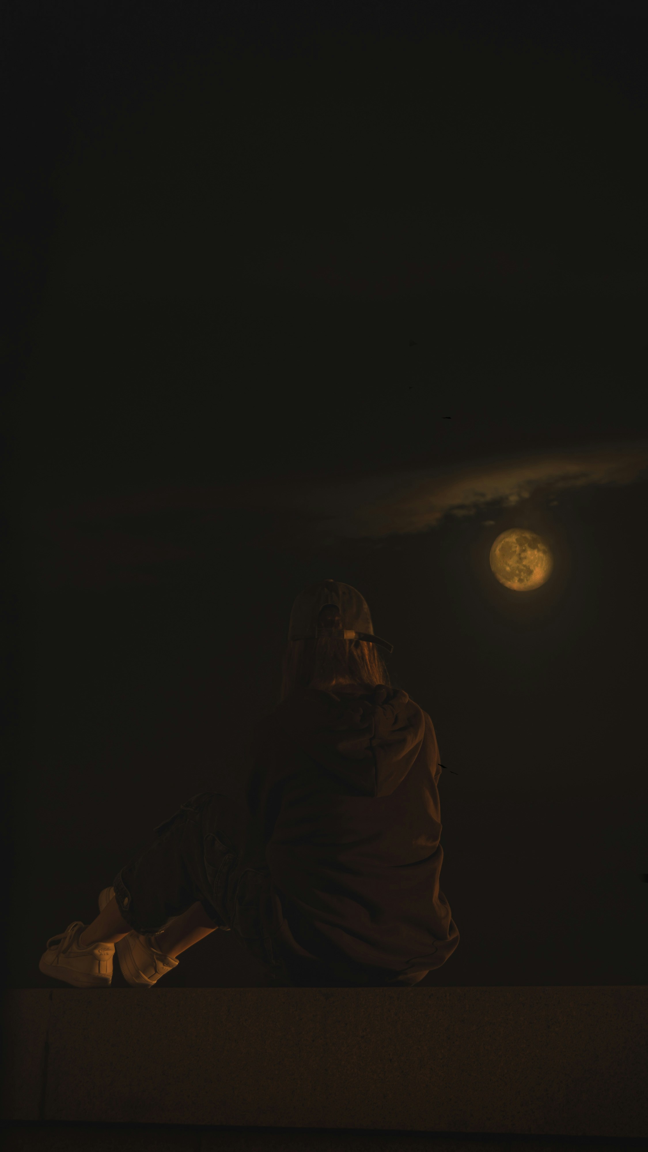 Une personne assise sur un rebord dans l’obscurité