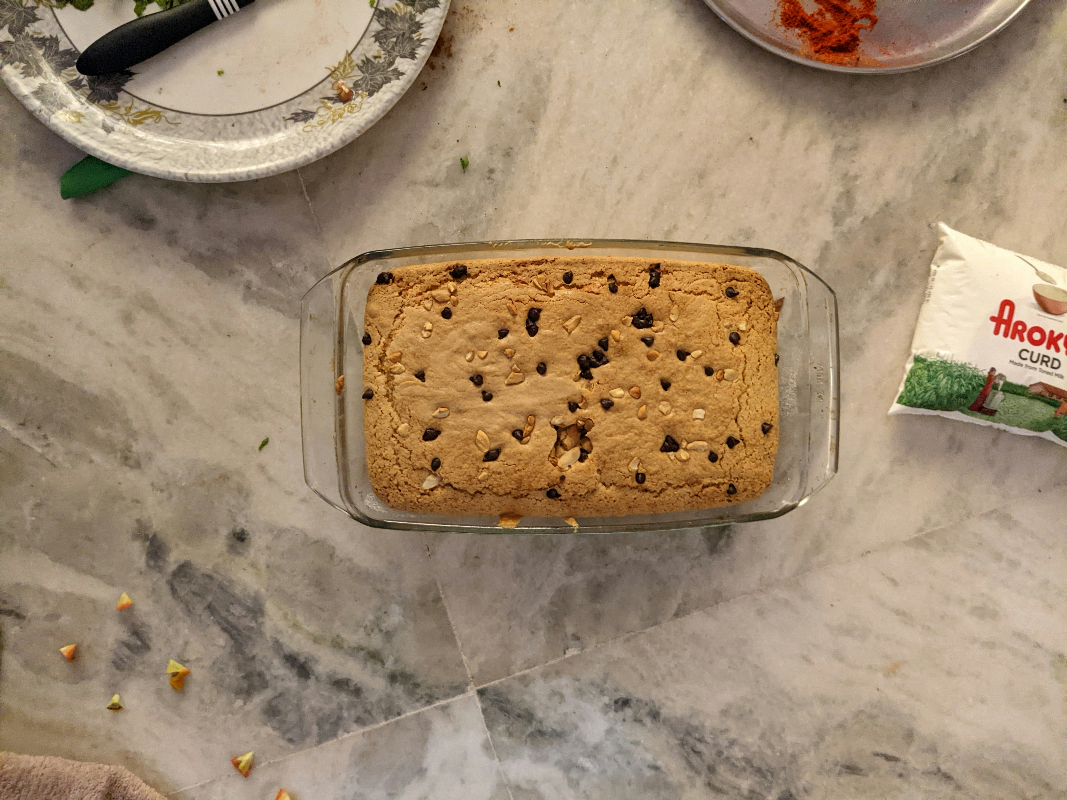 Kue chocolate chip dengan cokelat meleleh, pencahayaan bakery emas hangat, permukaan bersih cerah