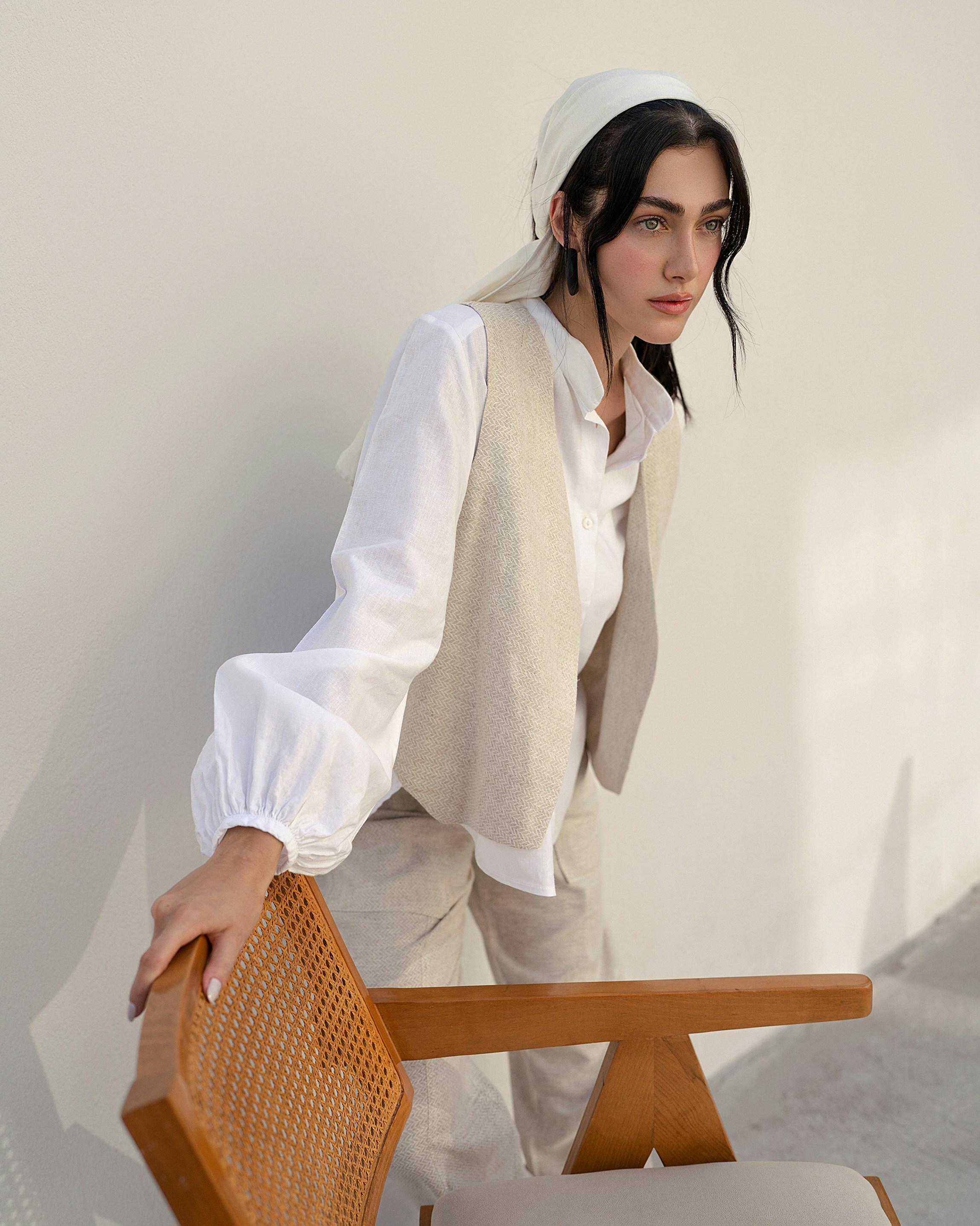 A woman leaning on a chair with her hand on the back of it