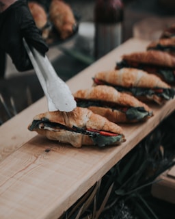 A wooden table topped with a cut in half sandwich