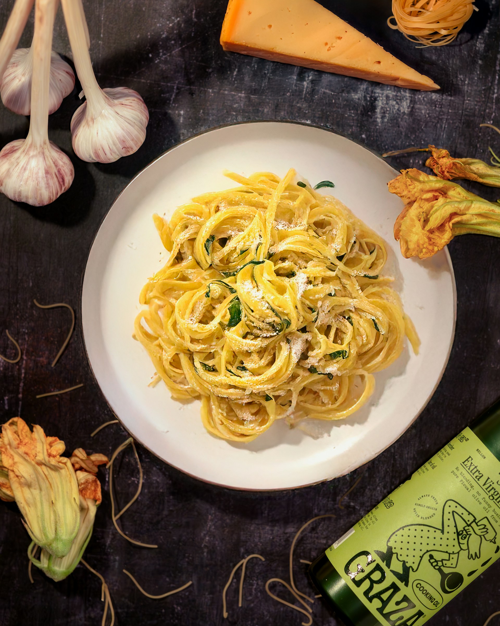 A plate of pasta with garlic, parmesan cheese, and a bottle of