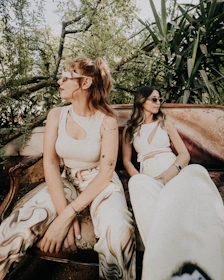 A couple of women sitting on top of a wooden bench