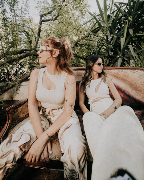 A couple of women sitting on top of a wooden bench