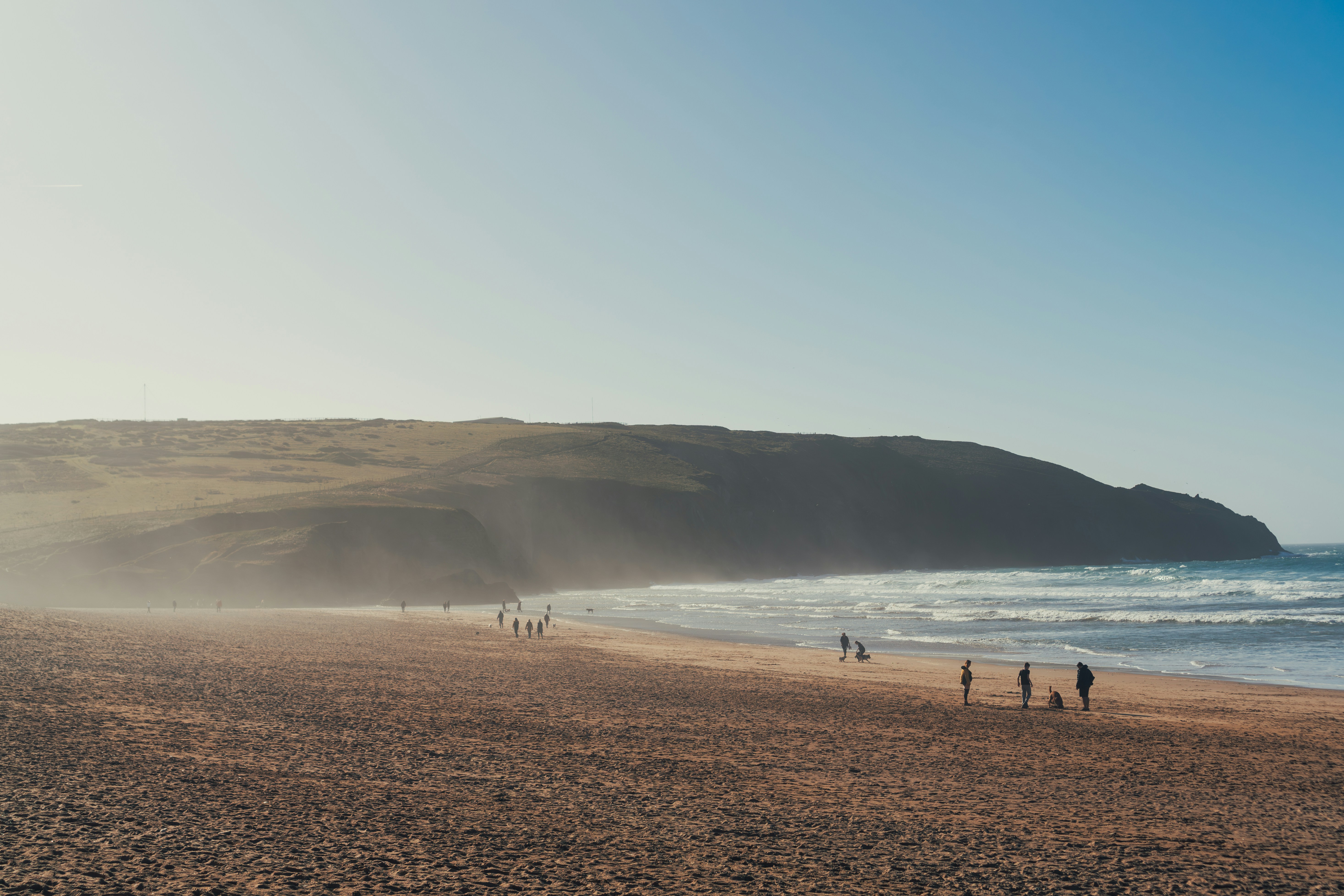 Un groupe de personnes debout au sommet d’une plage de sable