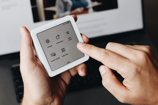 A person holding a tablet in front of a laptop