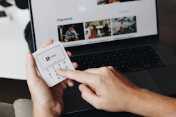 A person holding a remote control in front of a laptop