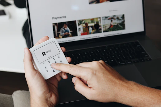 A person holding a remote control in front of a laptop