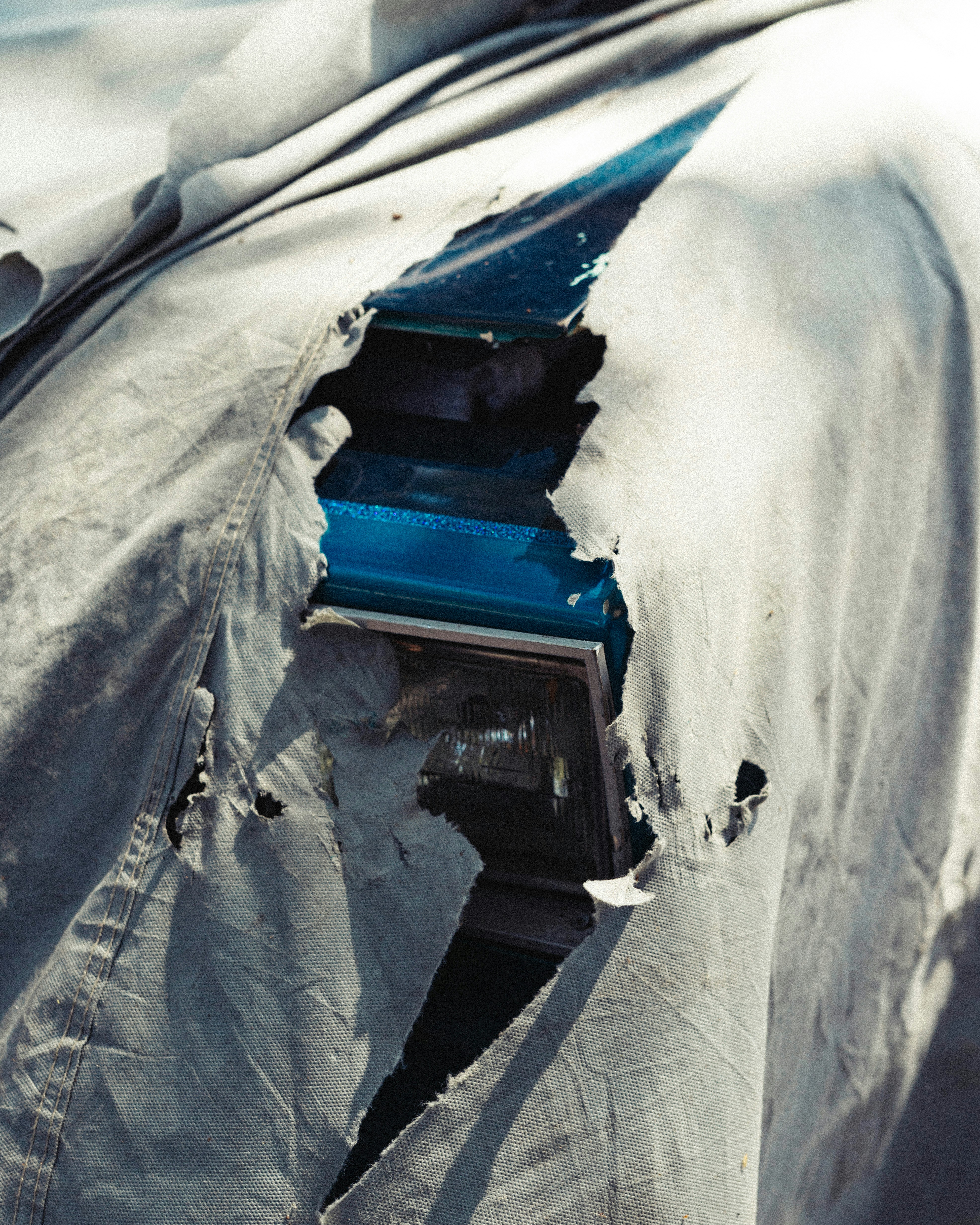 A car covered in a tarp with its hood up
