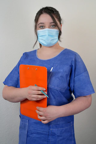 A woman wearing a surgical mask holding a clipboard