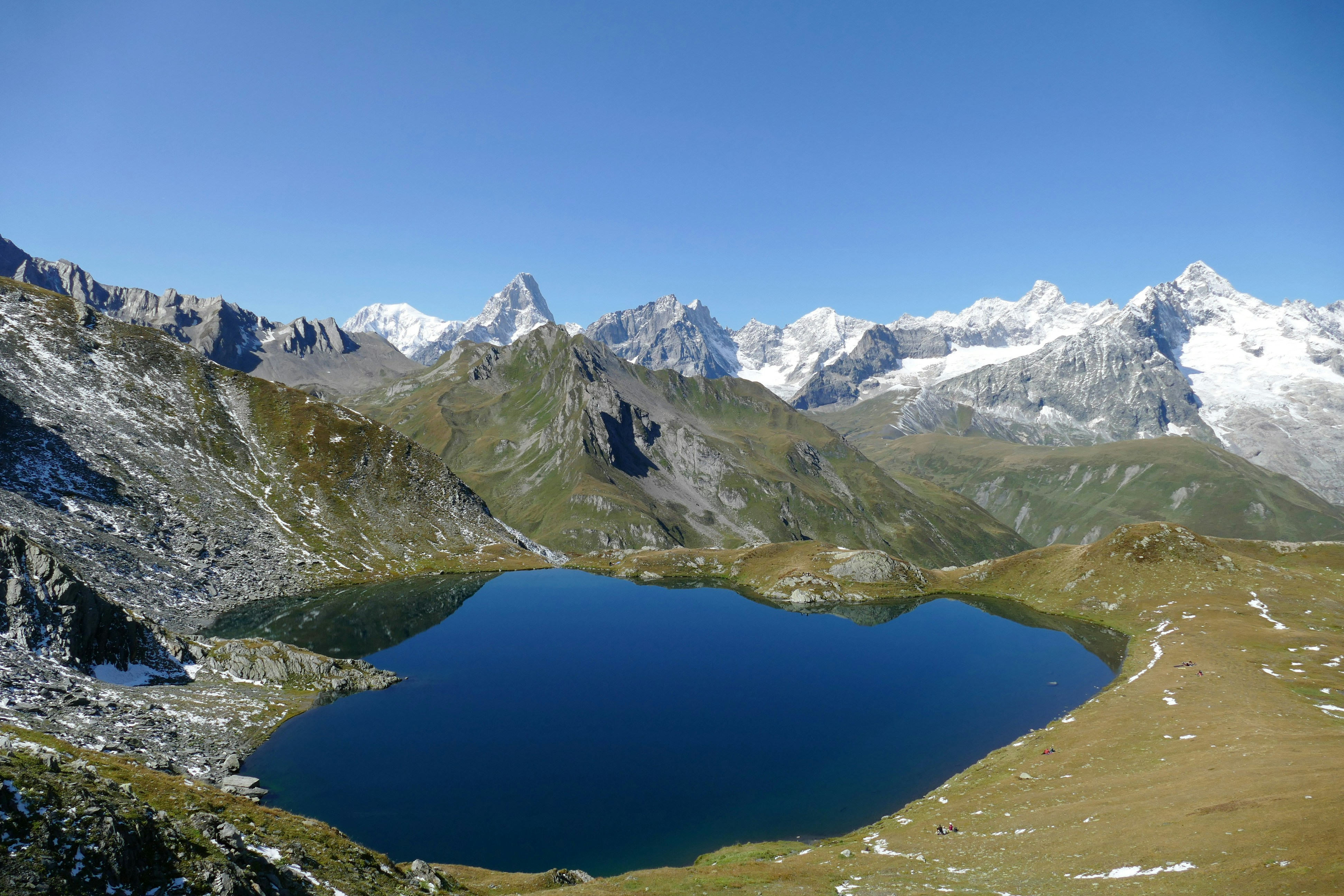 A mountain range with a lake surrounded by snow capped mountains