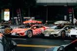 A group of cars driving down a street next to a tall building