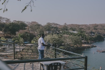 A man standing on top of a bridge next to a lake