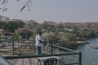 A man standing on top of a bridge next to a lake