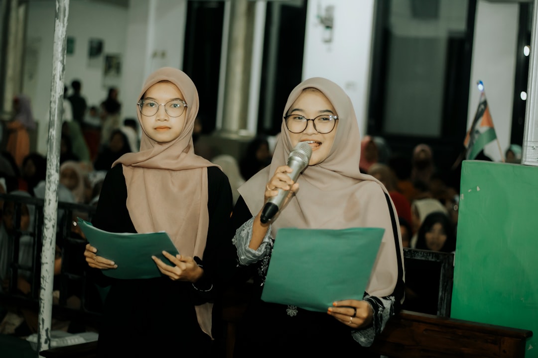 Two women in hijabs are holding microphones, girl muslim