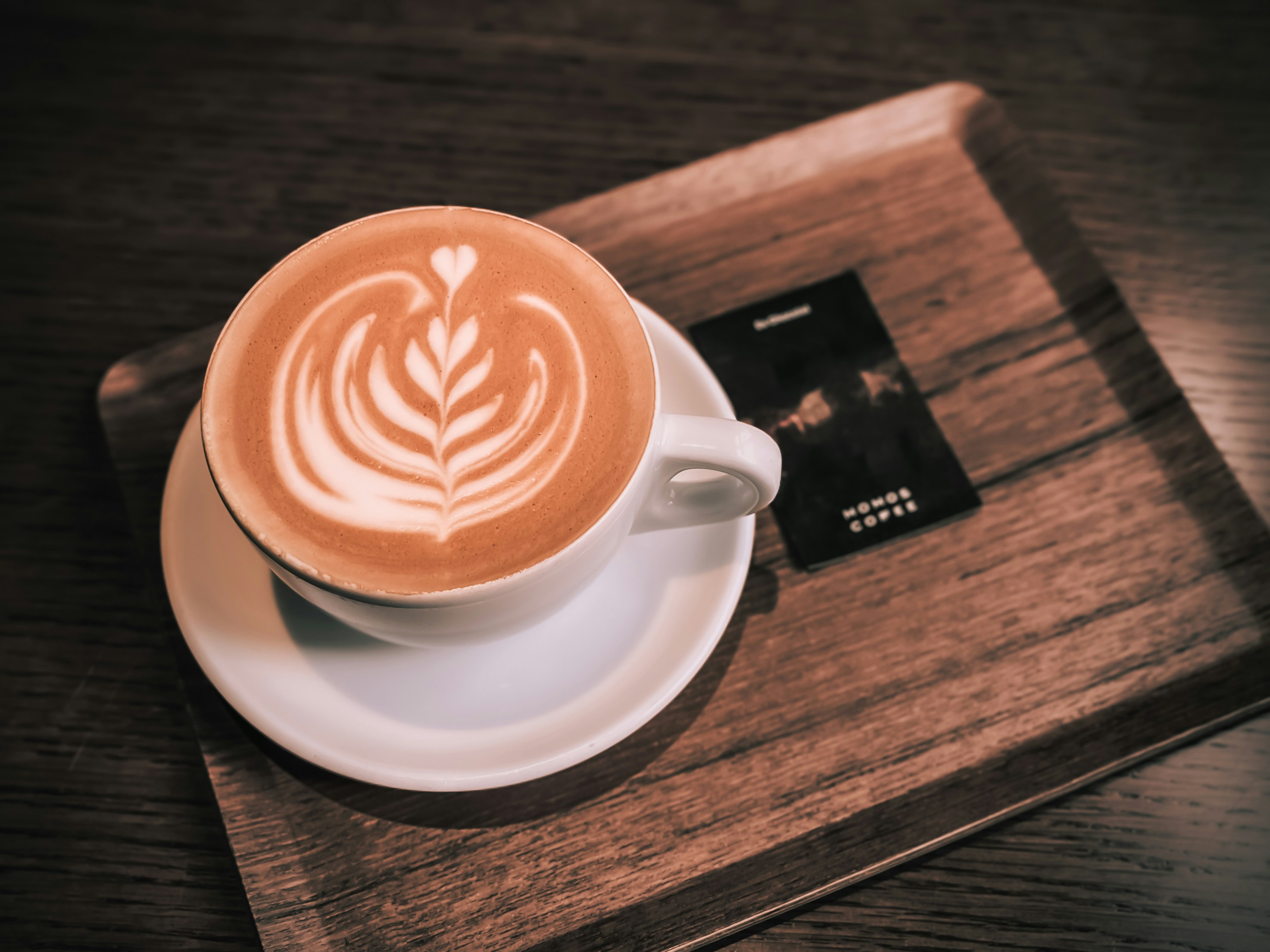 Cappuccino served on a wooden tray with a loyalty card