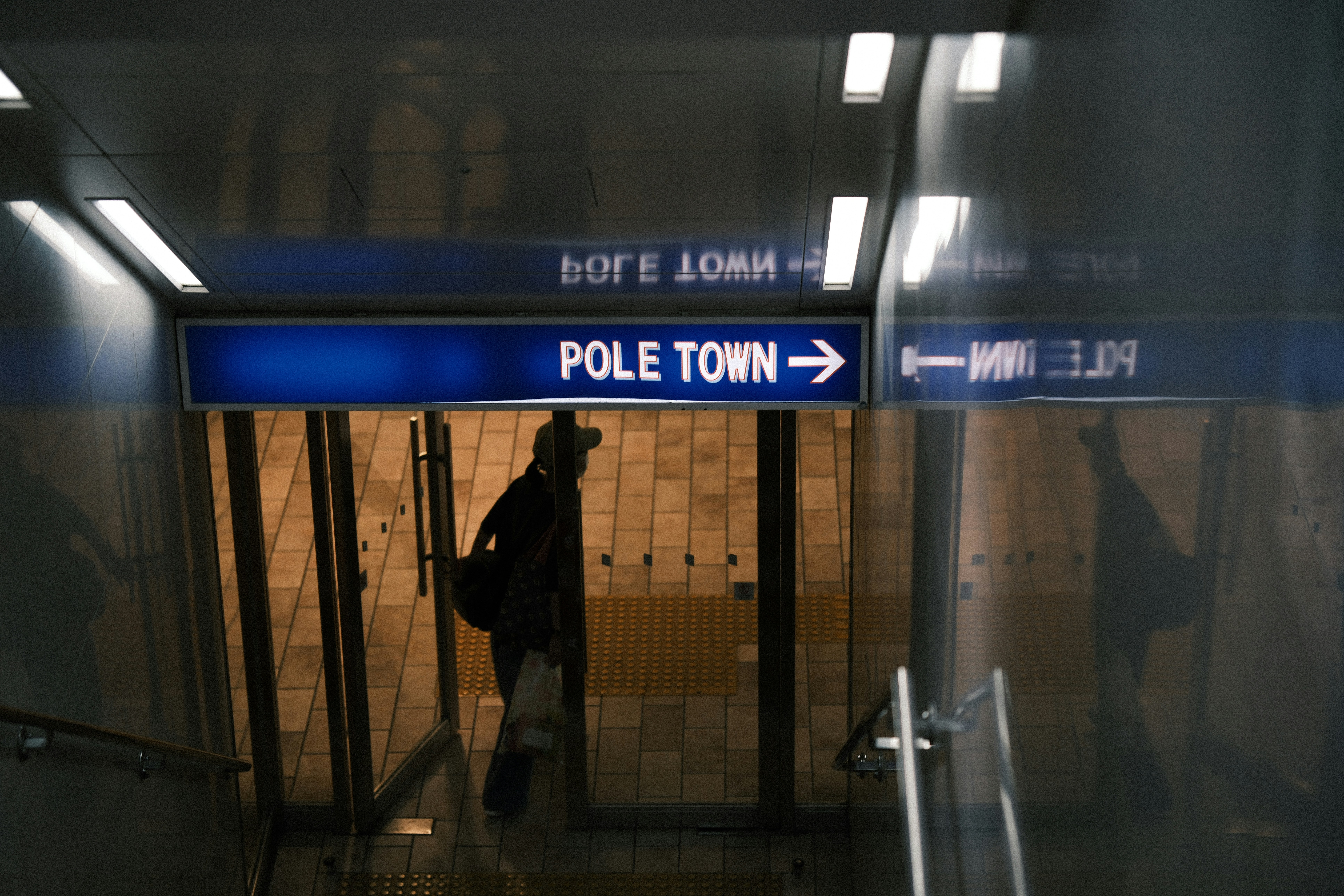 A person standing in a hallway next to a pole town sign