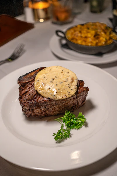 A white plate topped with a piece of meat covered in an elegant sauce, representing refined regional American fine dining