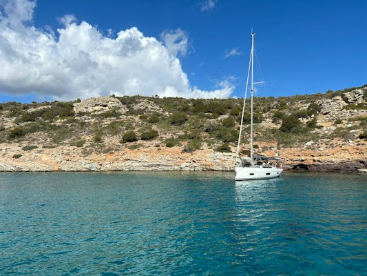 A sailboat in the water near a rocky shore — Hydra, Greece