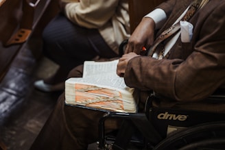 A man in a wheelchair reading a book