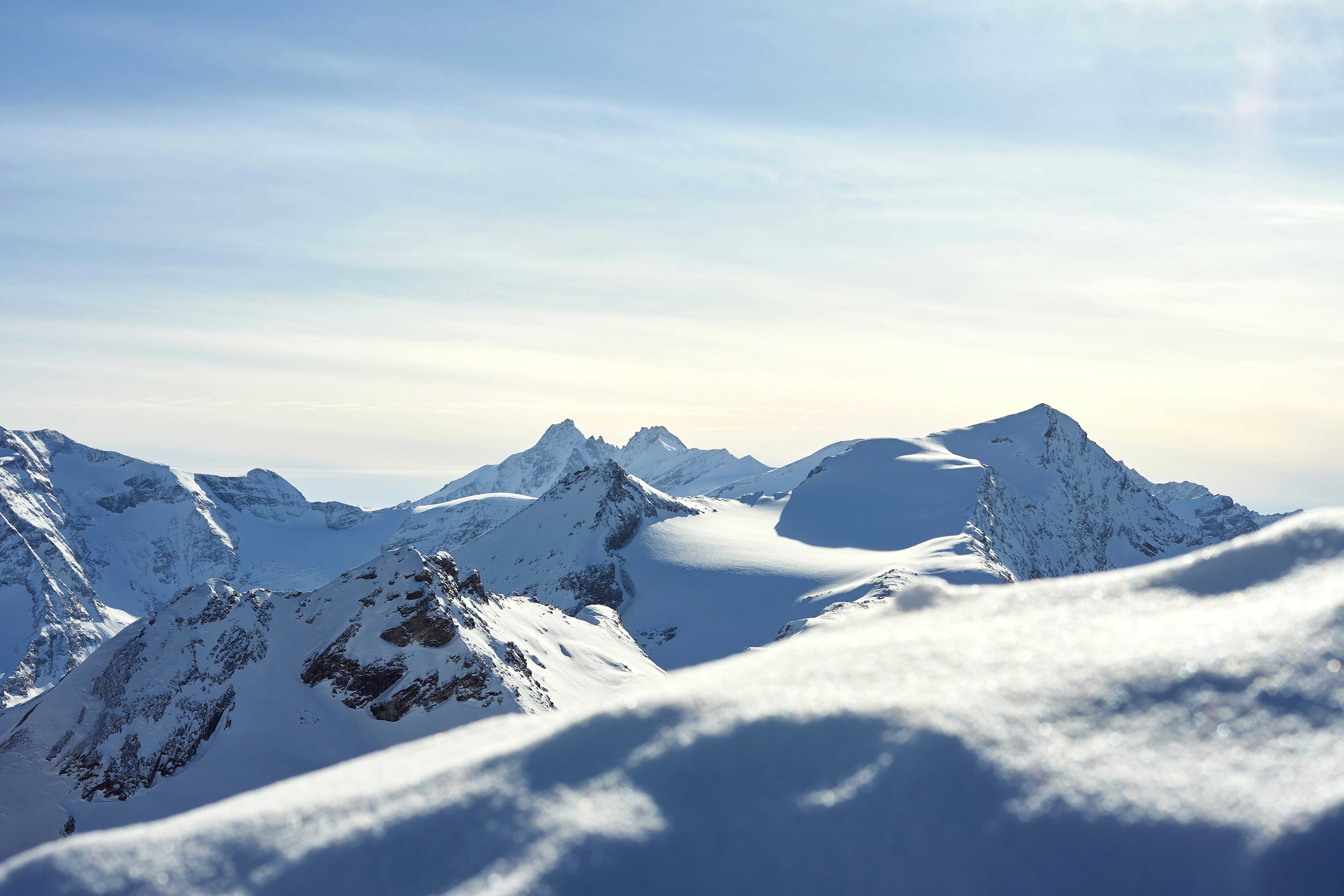A snowboarder is standing on top of a snowy mountain