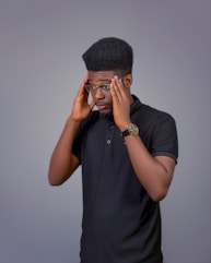 A man in a black shirt is holding his head