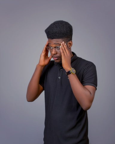 A man in a black shirt is holding his head