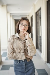 A woman wearing glasses standing in a hallway