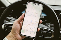 A person holding a cell phone while driving a car