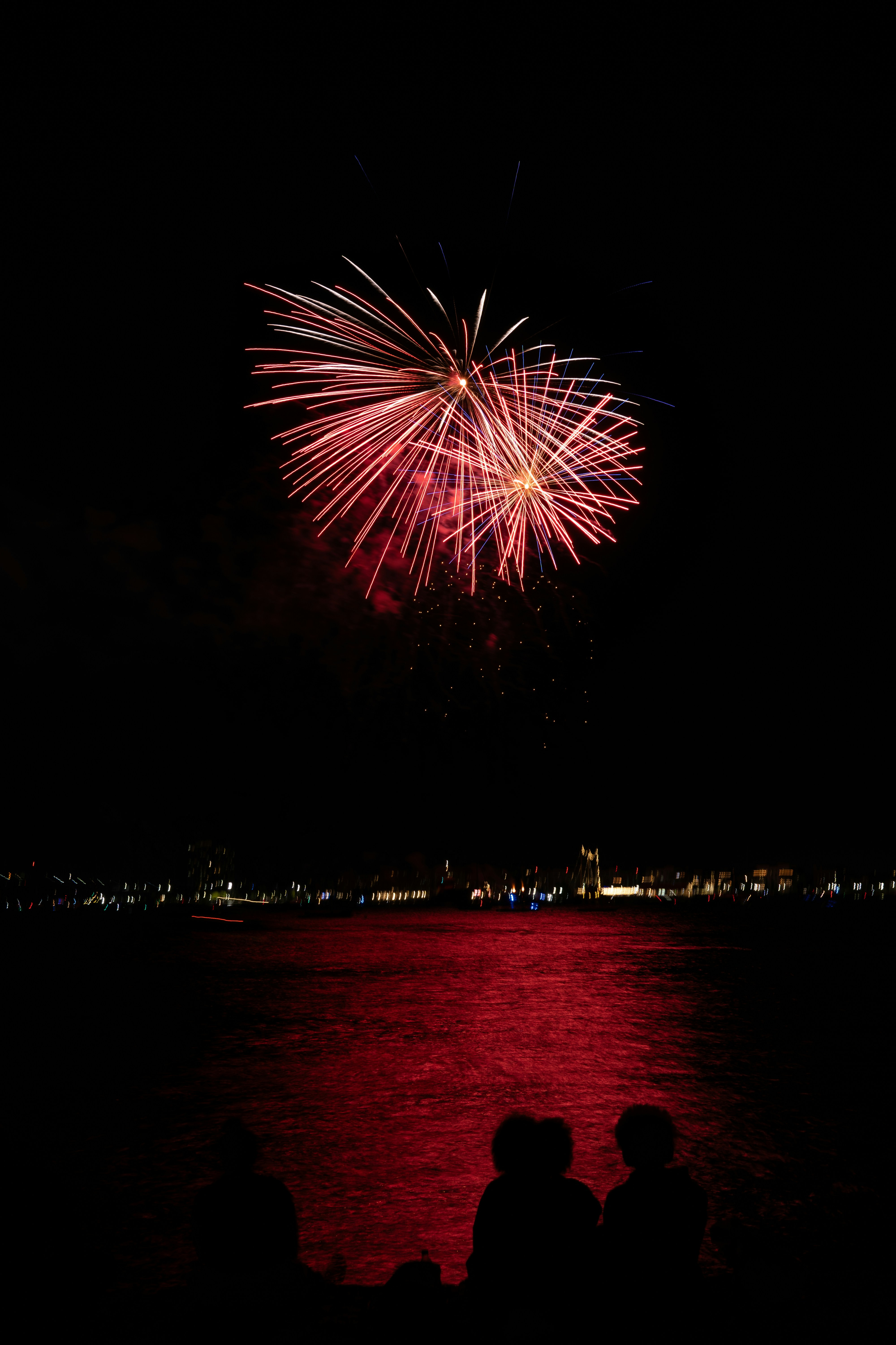 Fireworks are lit up in the night sky over a body of water