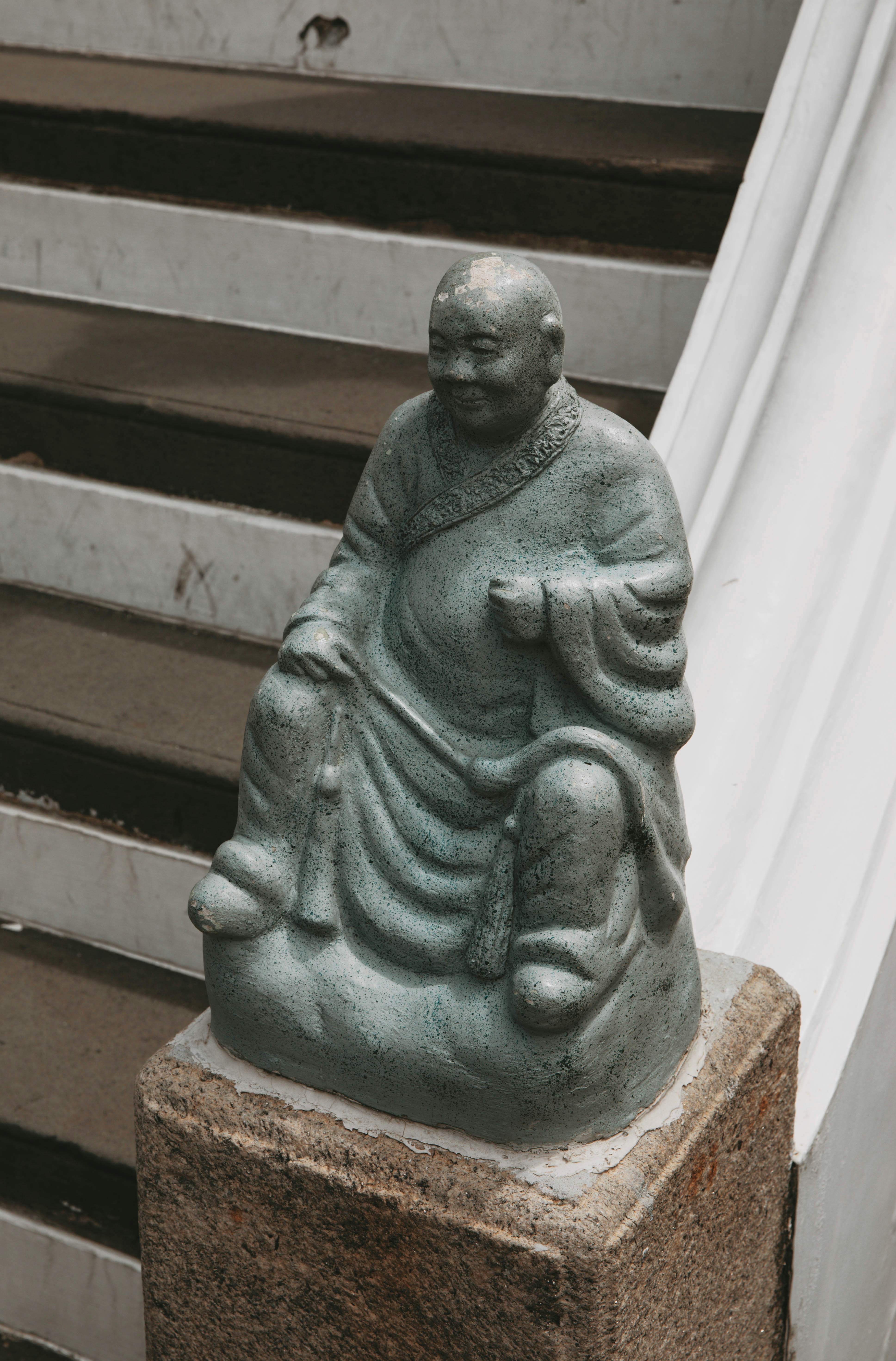 A statue of a person sitting on top of a cement block