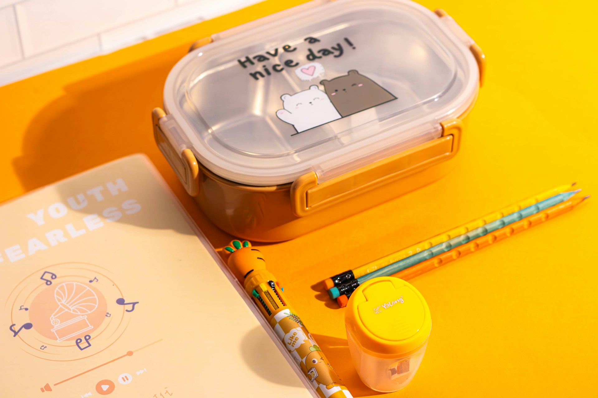 A yellow table topped with a container of food and a pencil
